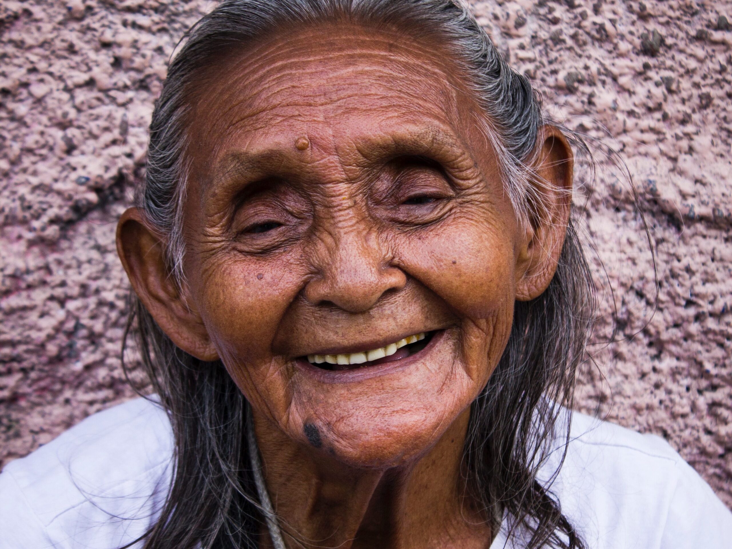 woman smiling while leaning on gray wall