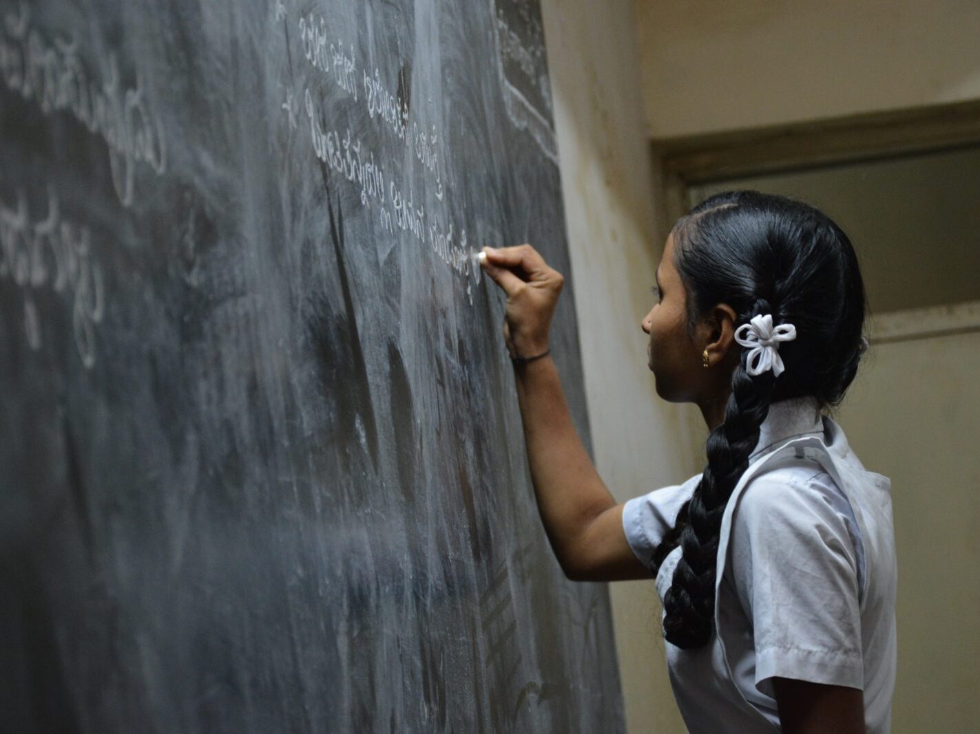 woman standing writing on black chalkboard